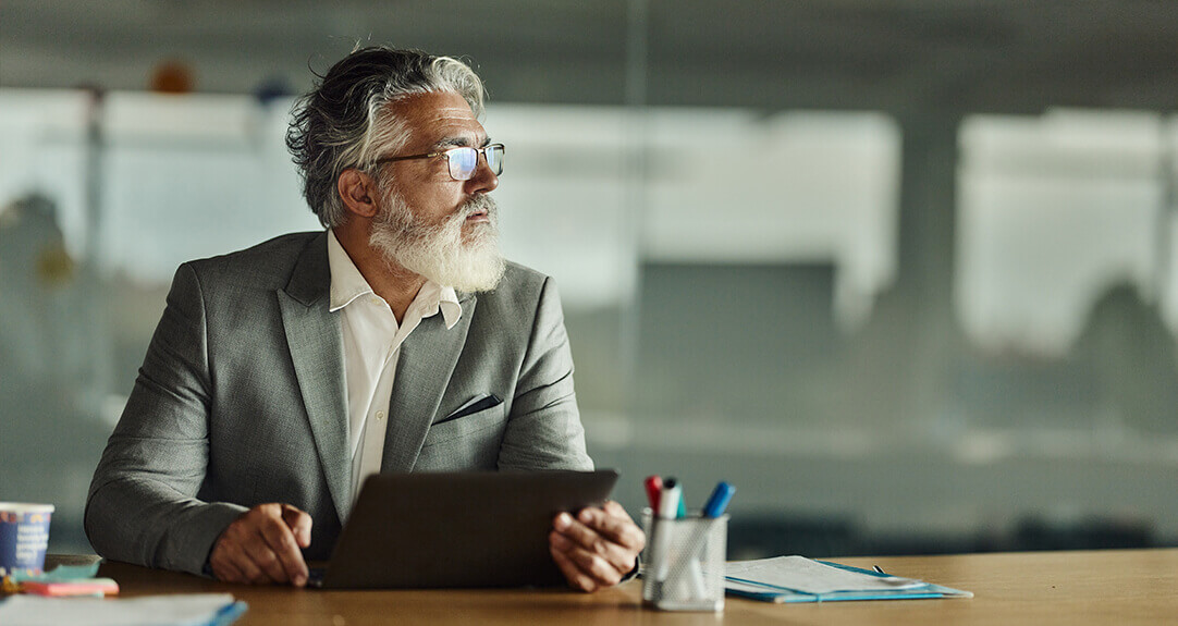 Mature businessman brainstorming at his office computer.